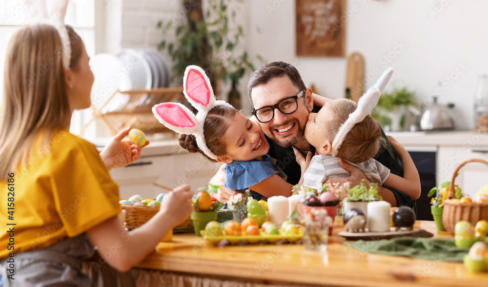 Happy children hugging and kissing father in kitchen