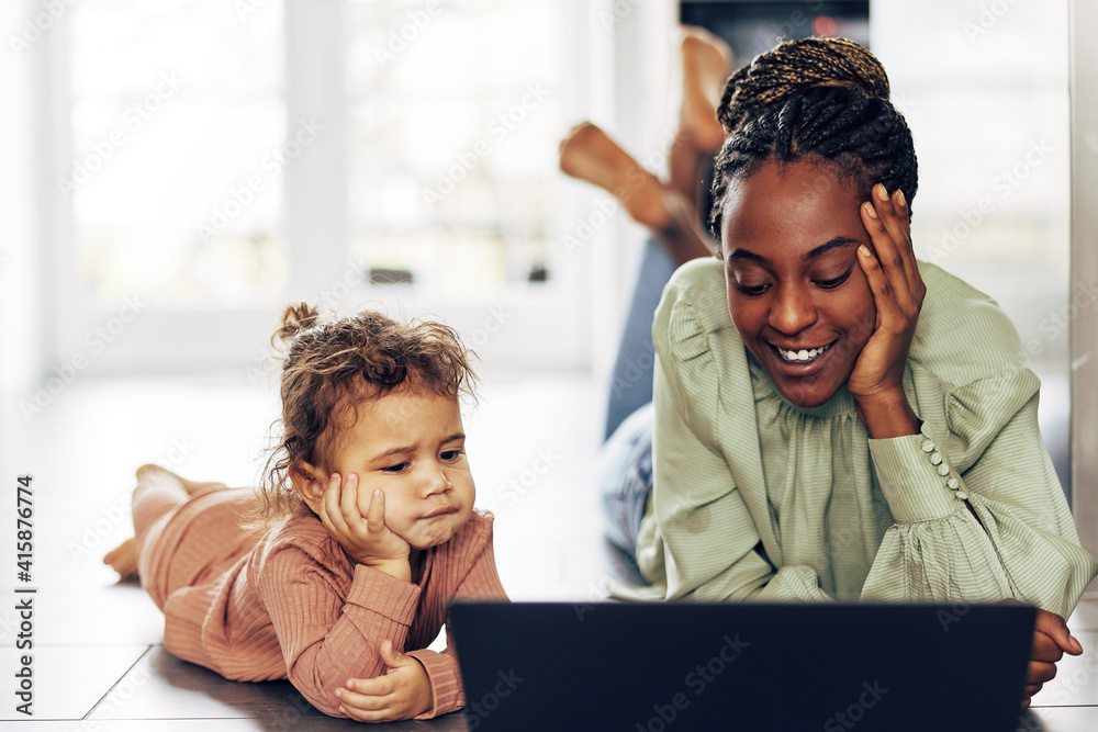 微笑的妈妈和她的小女儿在笔记本电脑上看东西