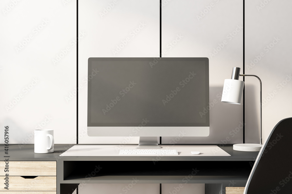 木桌上的黑色电脑显示器，配有灯、咖啡杯和键盘。实物模型