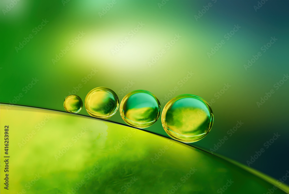 抽象明亮的彩色背景，绿色和黄色调的油和水滴，宏观.Cr