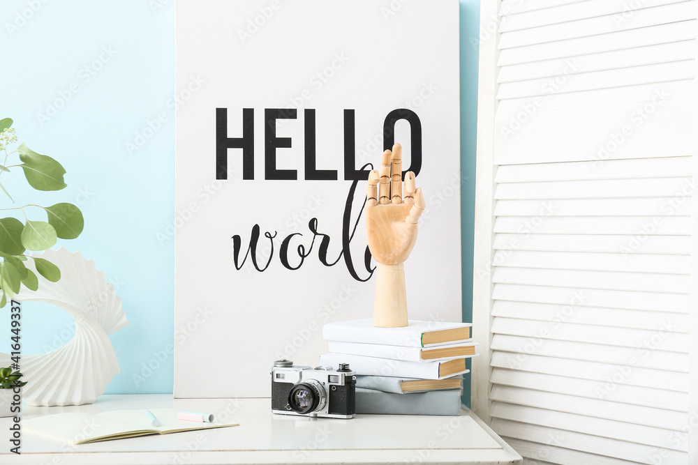 Wooden hand with books and photo camera on table in interior of room