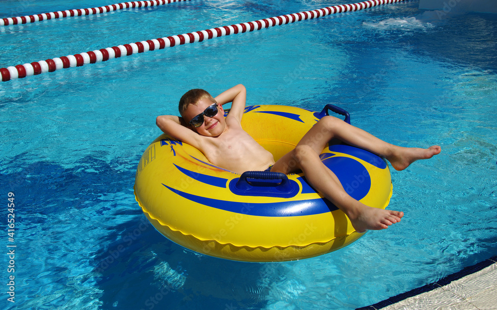 男孩在游泳池的充气环上放松。