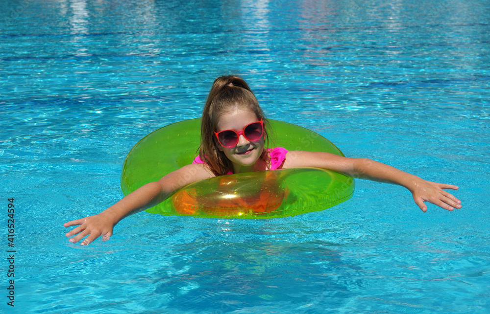 游泳池里戴着充气环的快乐小女孩。