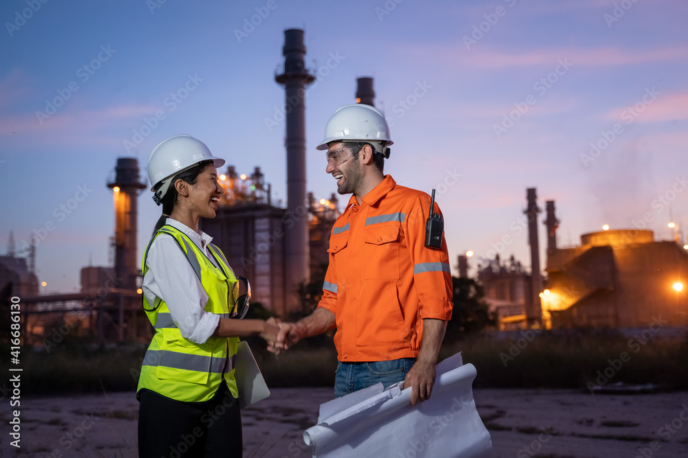 炼油厂行业工程师在炼油厂前进行团队合作时握手。