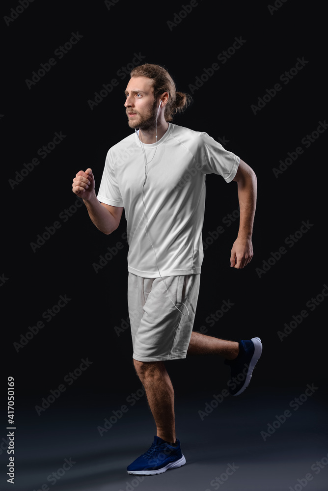 运动型男跑步者在黑暗背景下听音乐