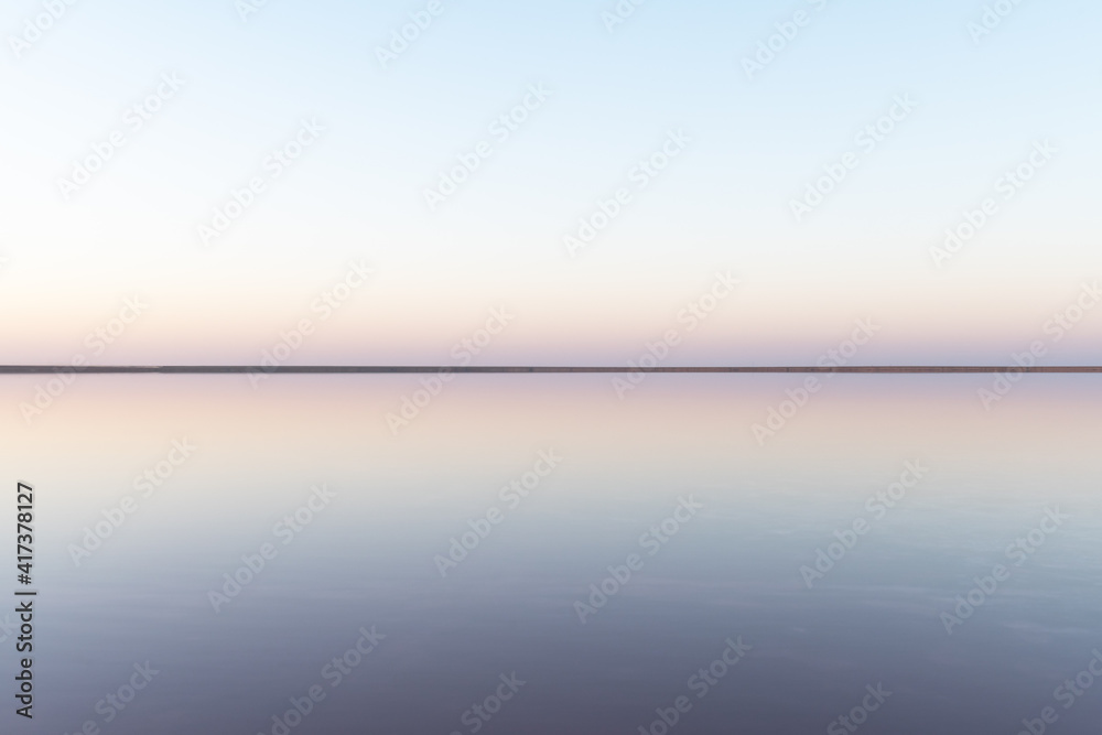宁静的极简主义景观，粉色盐湖表面光滑，平静的水面和地平线
