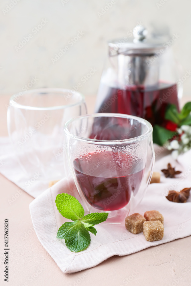 Glass of hot hibiscus tea on light background