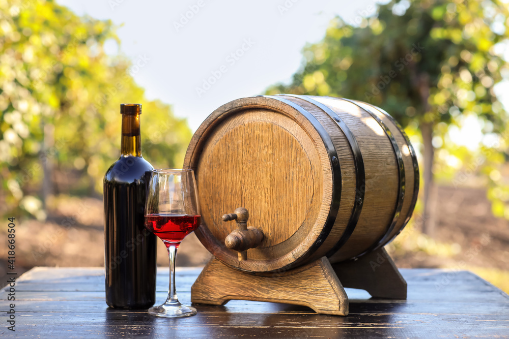 葡萄园餐桌上的一桶、一瓶和一杯葡萄酒