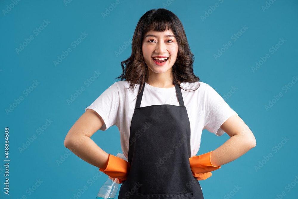 一张照片，照片中一名身穿围裙、戴着手套的亚洲妇女正在准备清洁工作
