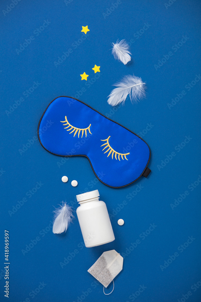 蓝色睡眠面罩，蓝色背景的药丸和草药茶，休息的概念，睡眠质量，好