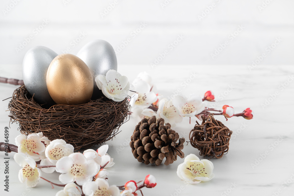 白色梅花巢中金色和银色复活节彩蛋的特写。
