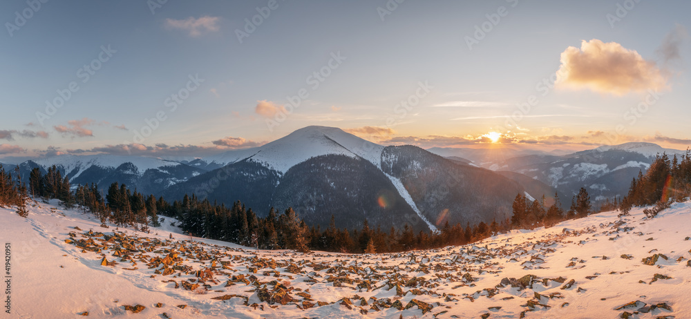 Fantastic winter landscape panorama in snowy mountains glowing by evening sunlight. Dramatic wintry 