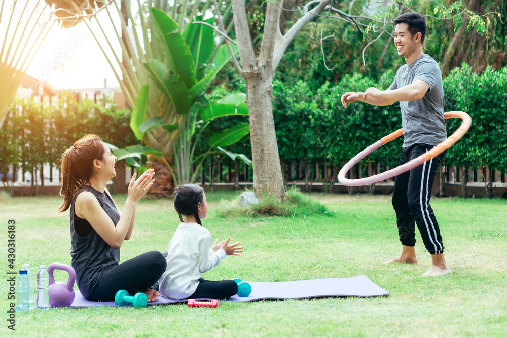 快乐的亚洲家庭正在愉快地一起在公园里享受瑜伽。