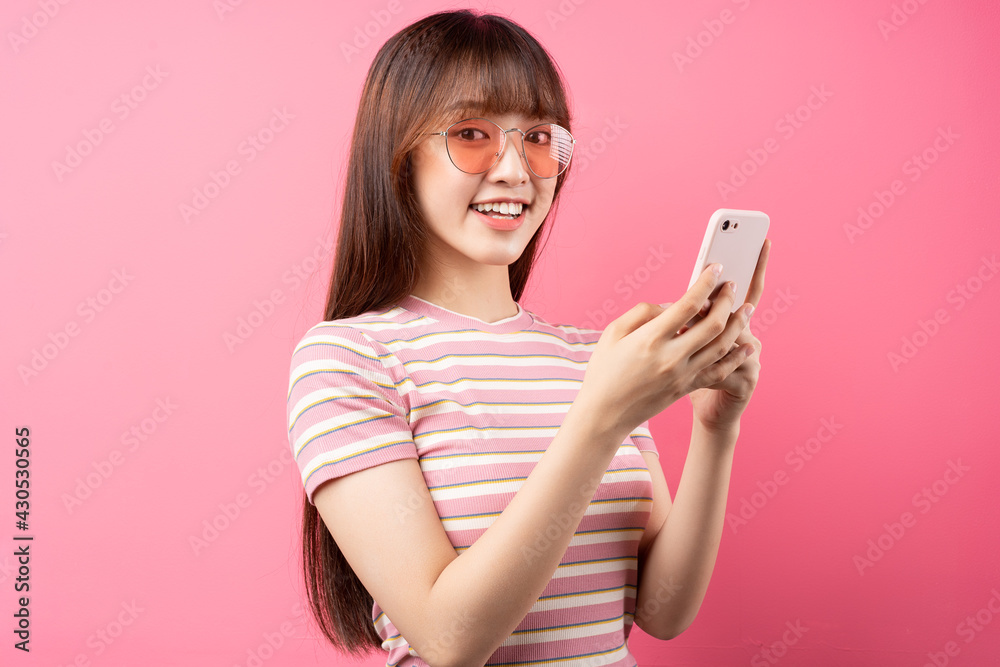 年轻的亚洲女孩在粉色背景下穿着粉色t恤的照片