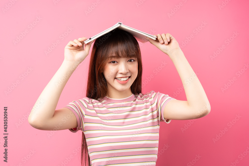 年轻的亚洲女孩在粉色背景下穿着粉色t恤的照片