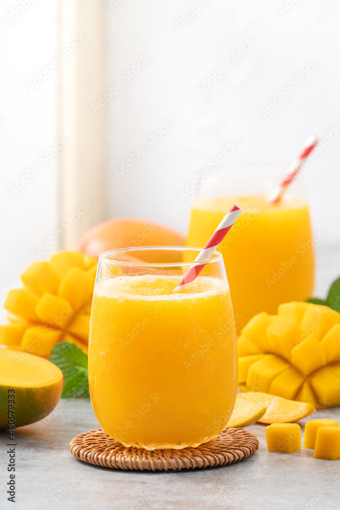 Fresh mango juice smoothie in a glass cup on gray table background.