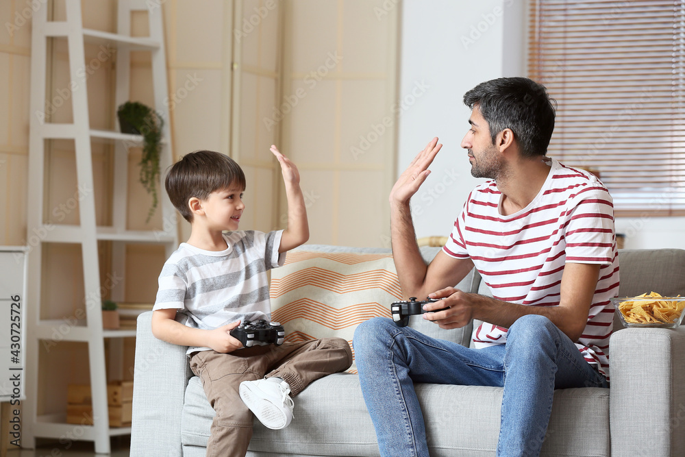 父亲和小儿子在家玩电子游戏
