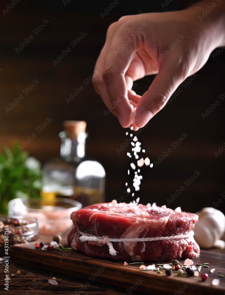 在砧板上用手在新鲜生牛肉上撒盐
