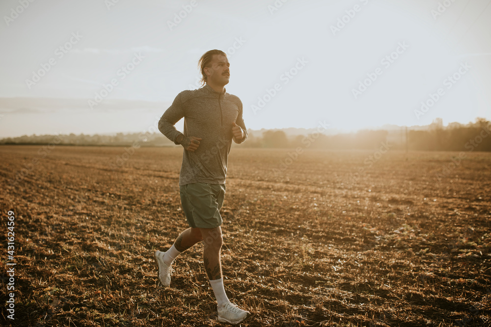 穿着运动服的活跃男子在乡村跑步