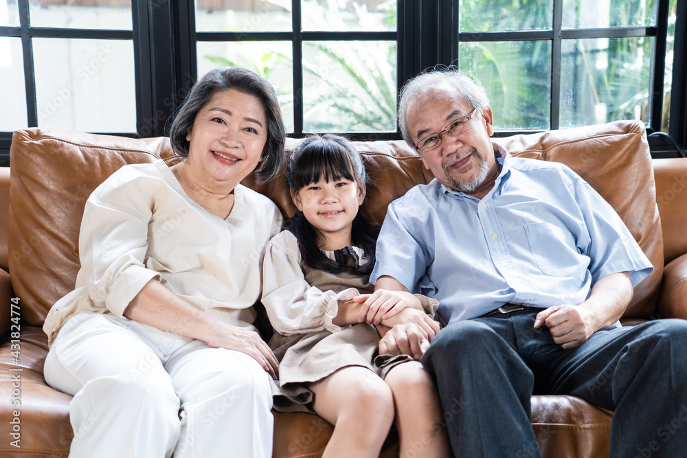 亚洲祖父母和孙女坐在沙发上的肖像。