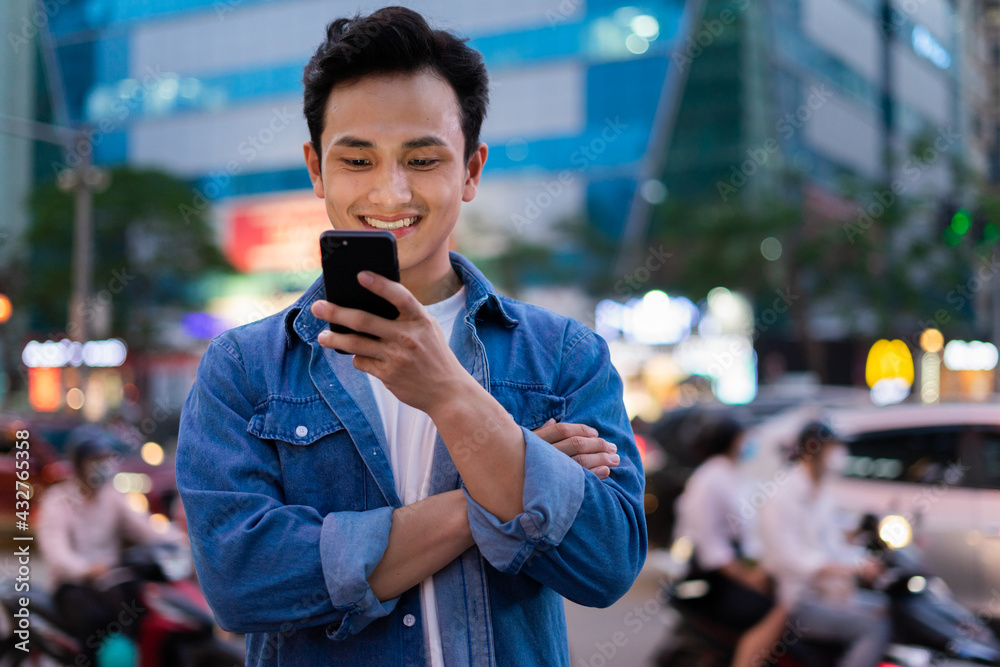 亚洲年轻男子晚上在街上使用智能手机