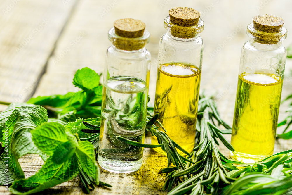 cosmetic oil in bottle with herbs on light table background