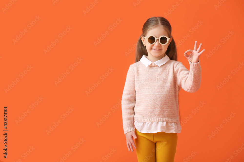 可爱的小女孩戴着时尚的太阳镜，在彩色背景上表现得很好