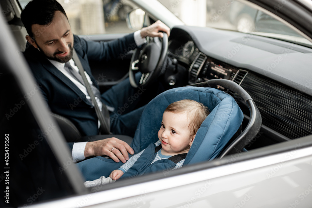 父亲开车上班时照顾孩子，孩子坐在现代汽车座椅上。孩子新出生的旅行