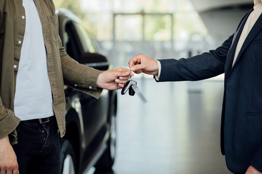新汽车。经销商给新主人钥匙的特写。汽车经销商给顾客新车钥匙。