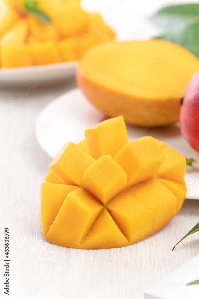 Diced fresh mango fruit on a white plate with leaves.