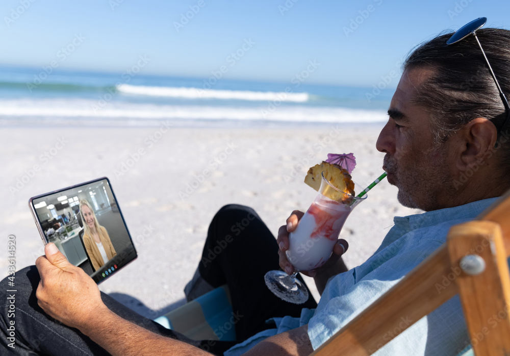 高加索男子在海滩上喝酒放松，用平板电脑进行视频通话