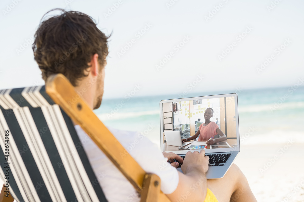 高加索男子在海滩上放松，用笔记本电脑进行视频通话