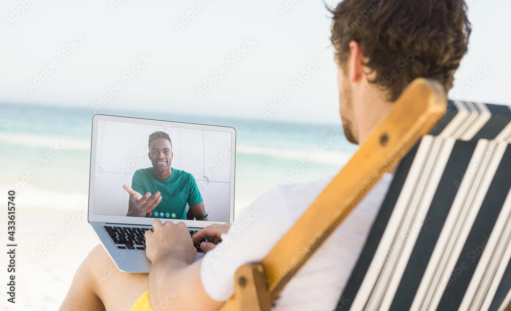 高加索男子在海滩上放松，用笔记本电脑进行视频通话