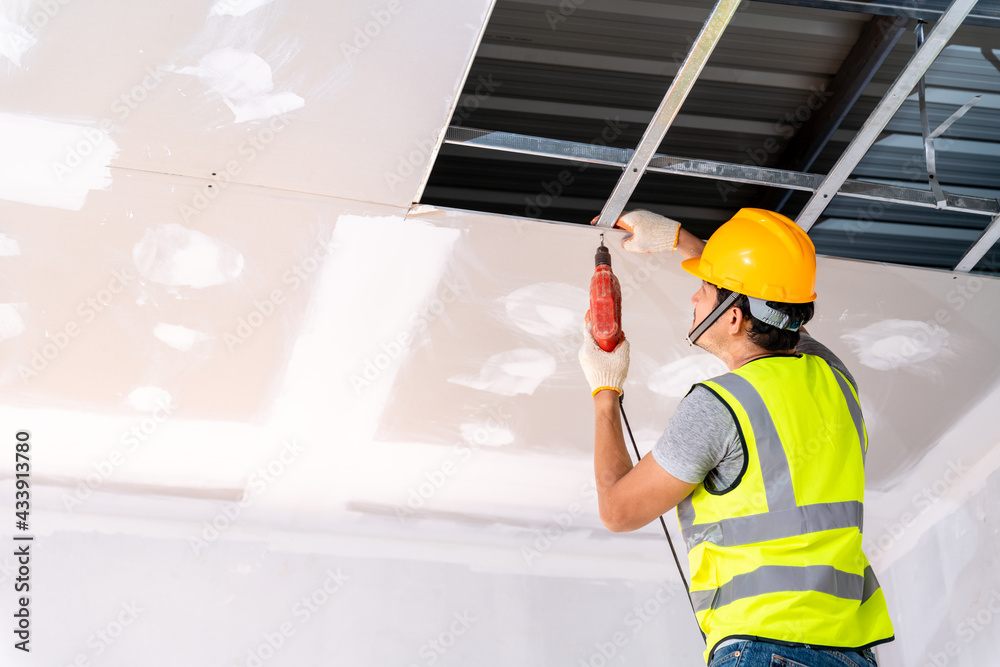 建筑工人正在使用电钻在建筑物中安装天花板