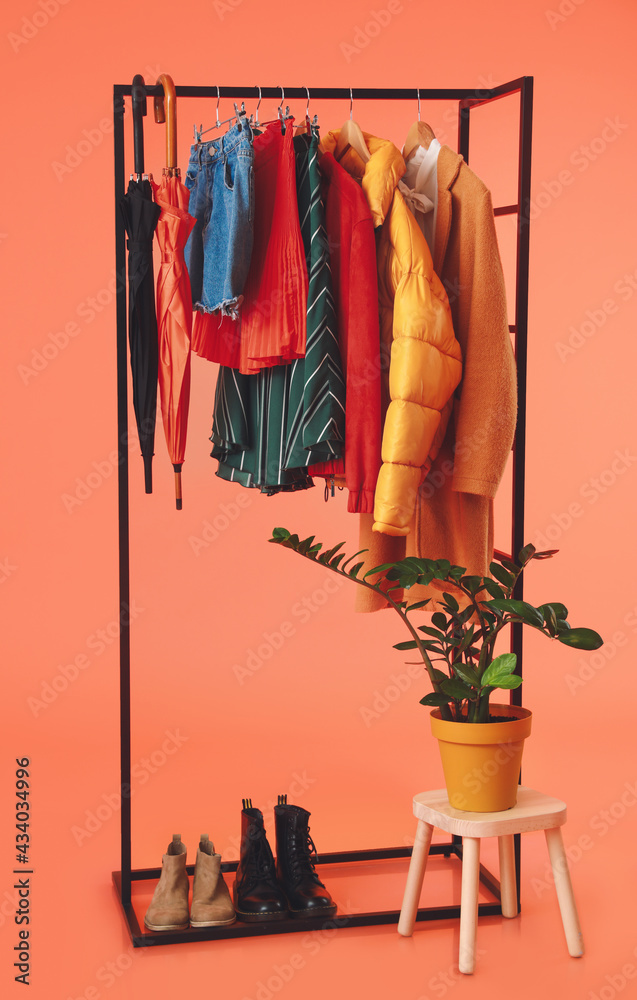 彩色背景上有时尚衣服、鞋子和雨伞的架子
