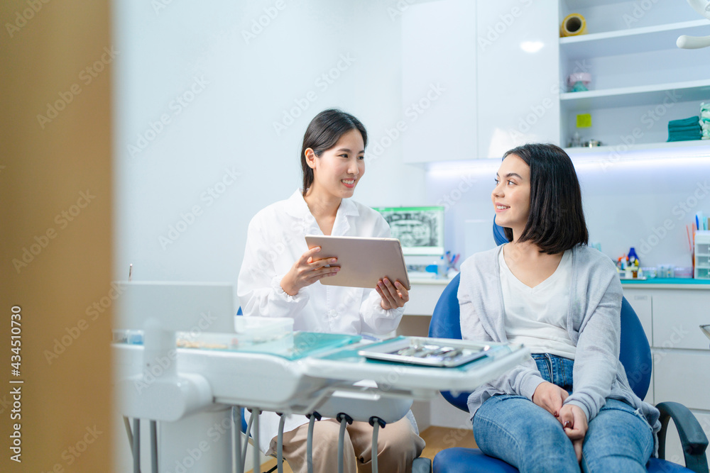 亚洲女牙医在药片上展示x光片，给出治疗建议。