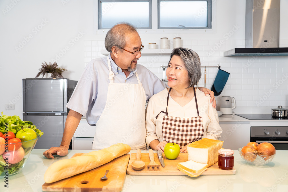 一对亚洲高级夫妇互相帮助做饭和准备食物。