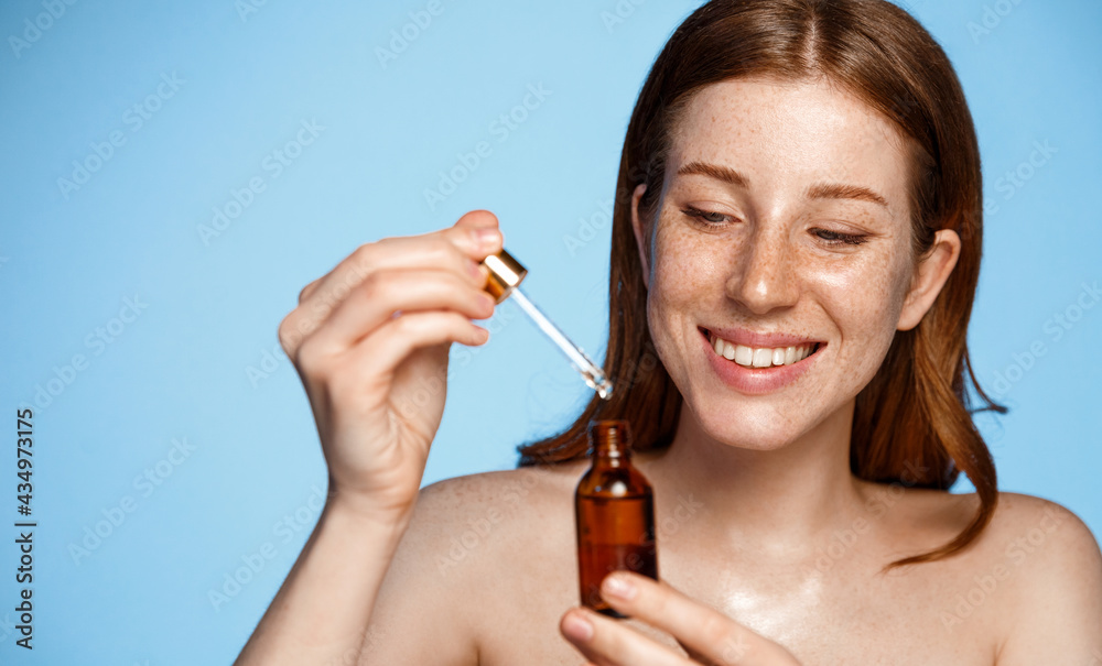 美丽。女人用一瓶精油滋润面部皮肤。面部护理