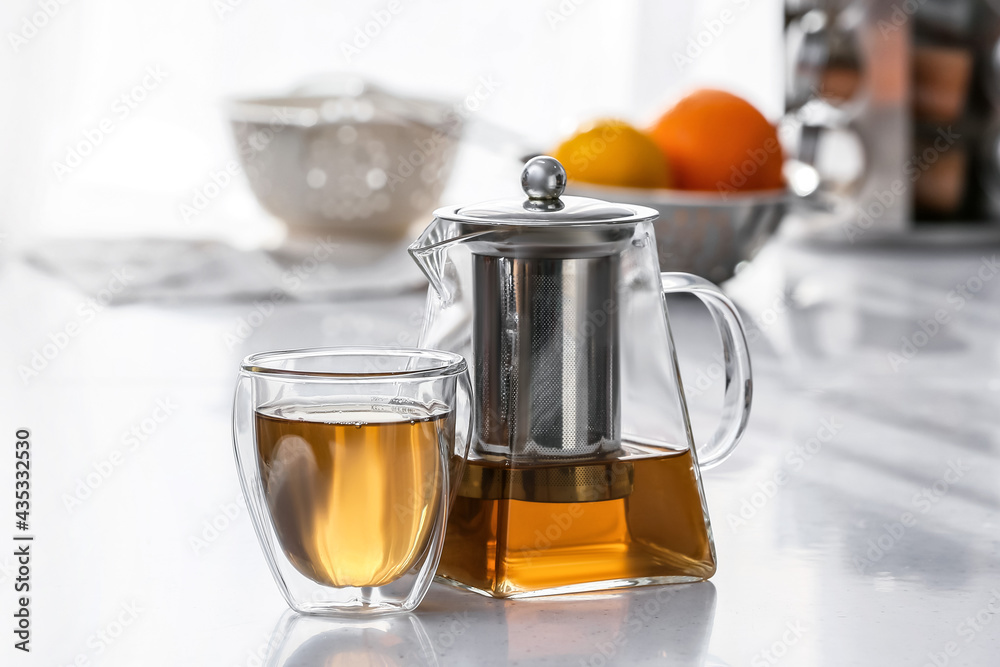厨房桌子上放着热茶的茶壶和玻璃杯
