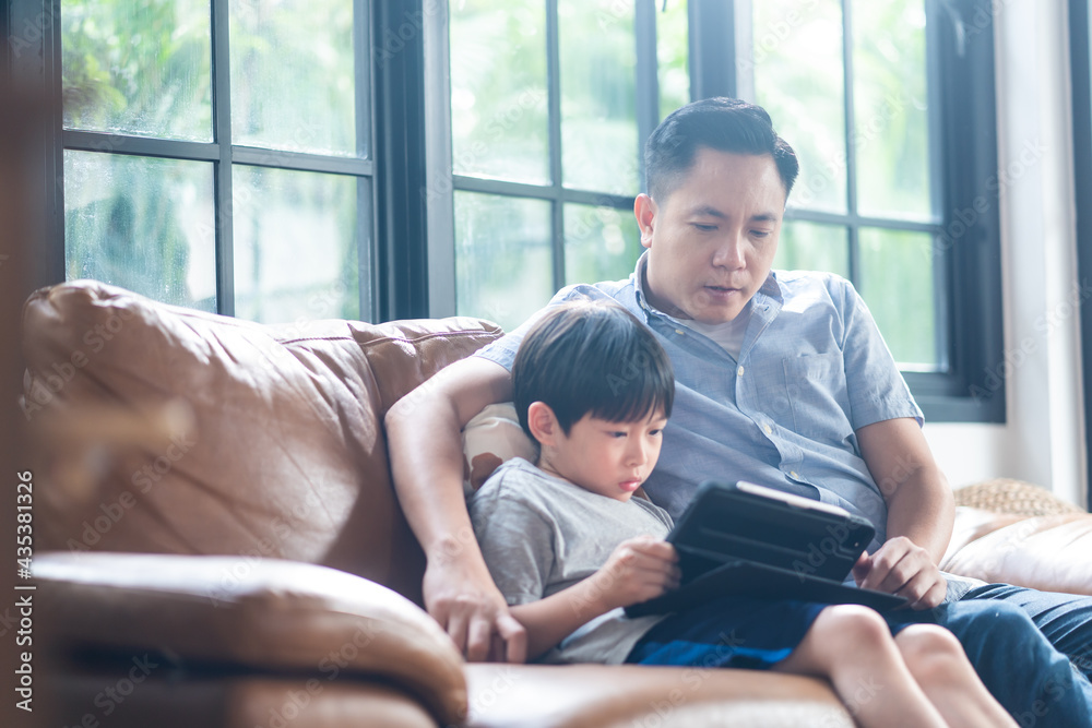 亚洲家庭学校男孩与父亲坐在一起，使用平板电脑在线学习