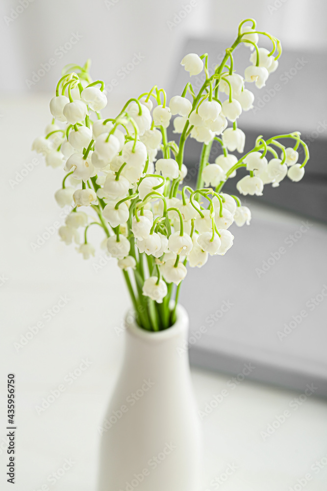 桌上摆着美丽的铃兰花的花瓶