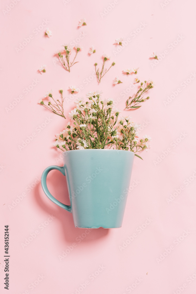 粉色背景下蓝色杯子里的菊花