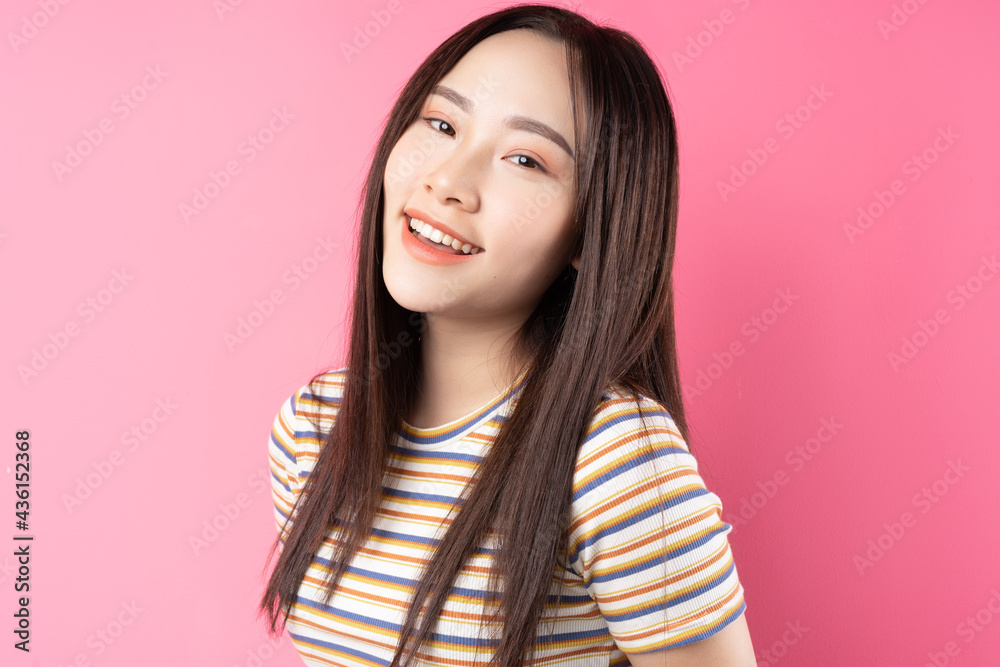 年轻的亚洲女性在粉色背景下摆姿势