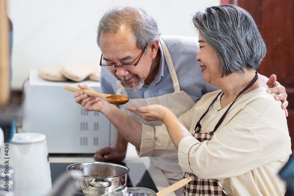 Senior older grandparent couple at house enjoy cook food in kitchen