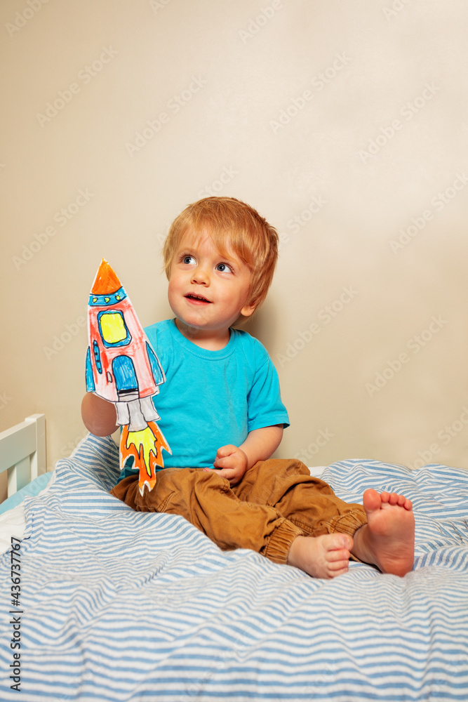 男婴坐在床上玩纸火箭
