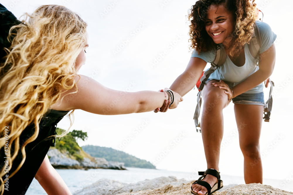 Young female hikers helping each other