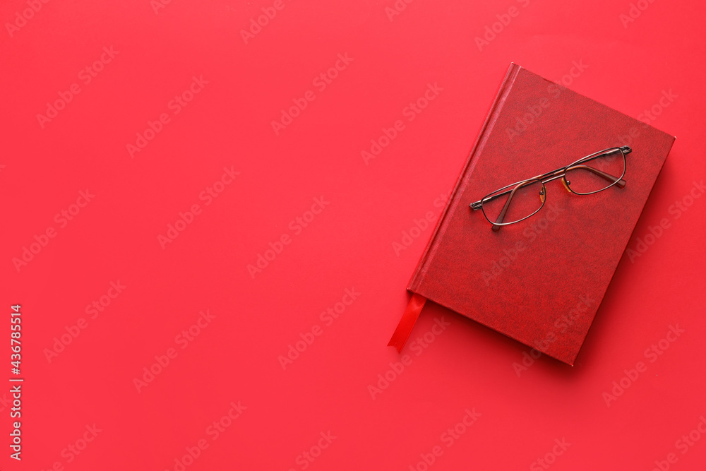 Book with bookmark and eyeglasses on color background