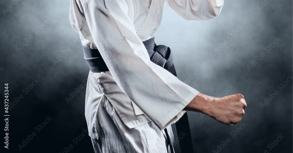 Composition of midsection of male martial artist with black belt over clouds of smoke