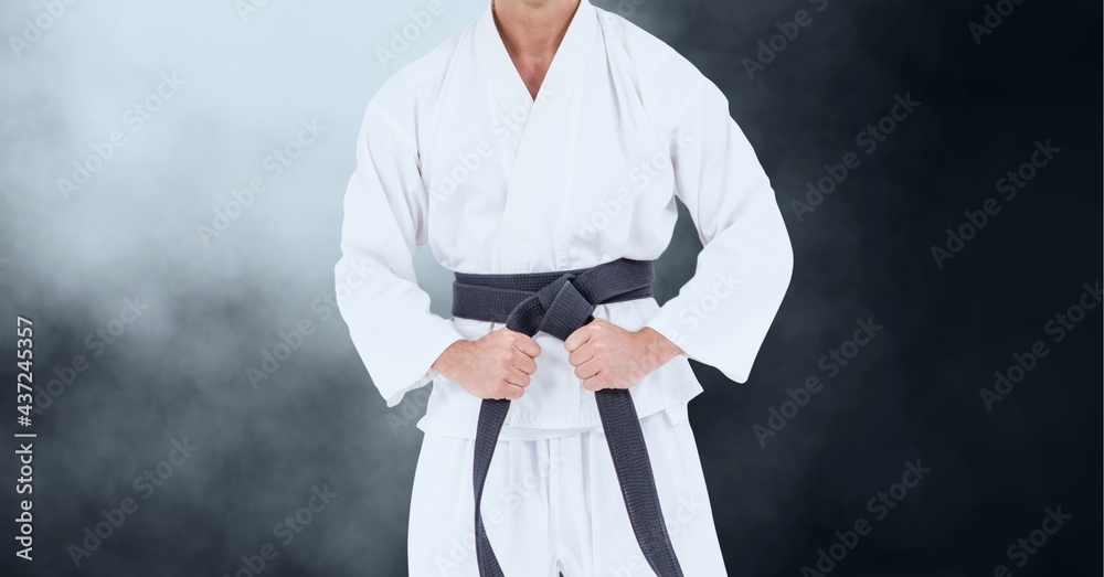 Composition of midsection of male martial artist with black belt over clouds of smoke