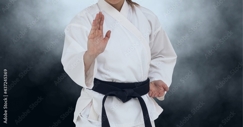 Composition of midsection of female martial artist with black belt over clouds of smoke